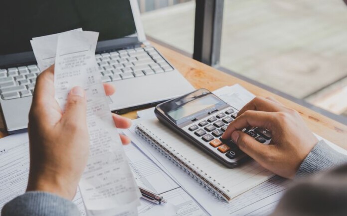 Young man using calculator and calculate bills in home office.